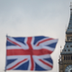 A Union Jack flag flutters in front of Big Ben in London, England.